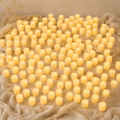 Hundred of small yellow candles on a textured beige surface