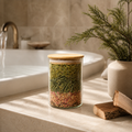 Glass jar with wooden lid on a bathroom counter with a plant and sink in the background