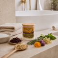 Jar of dried herbs on a bathroom counter with flowers and a bowl of salt.